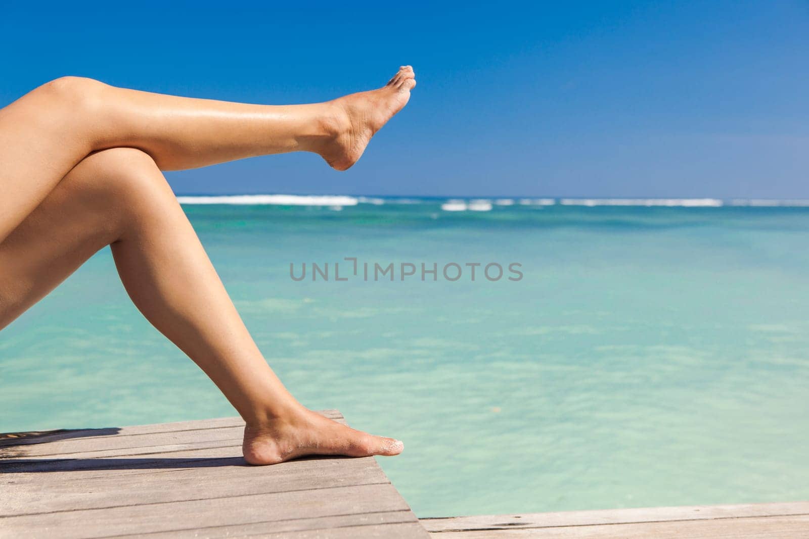 Beautiful female legs with a beautiful tropical beach as background