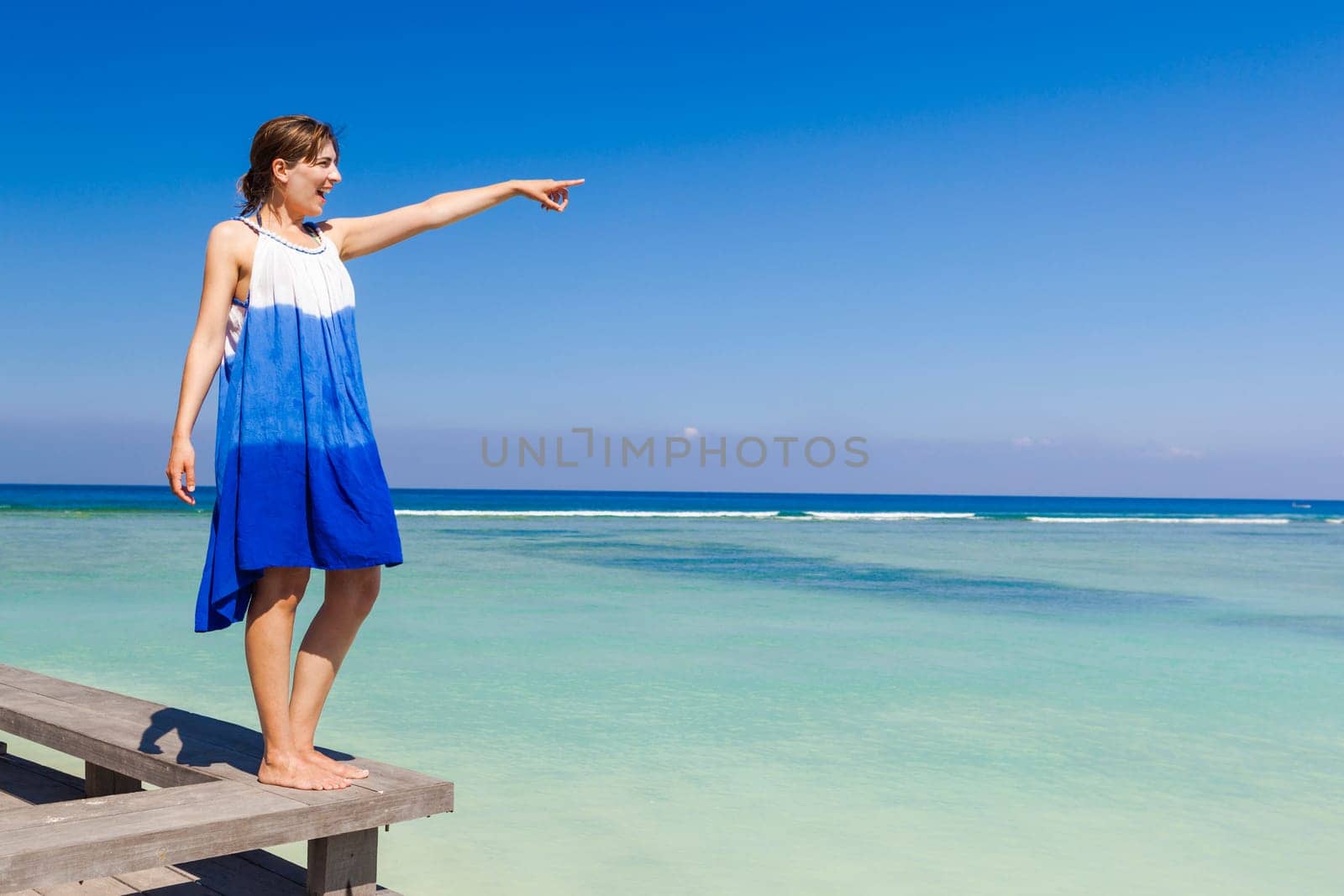 Beautiful woman on a beautiful tropical beach pointing to somewhere
