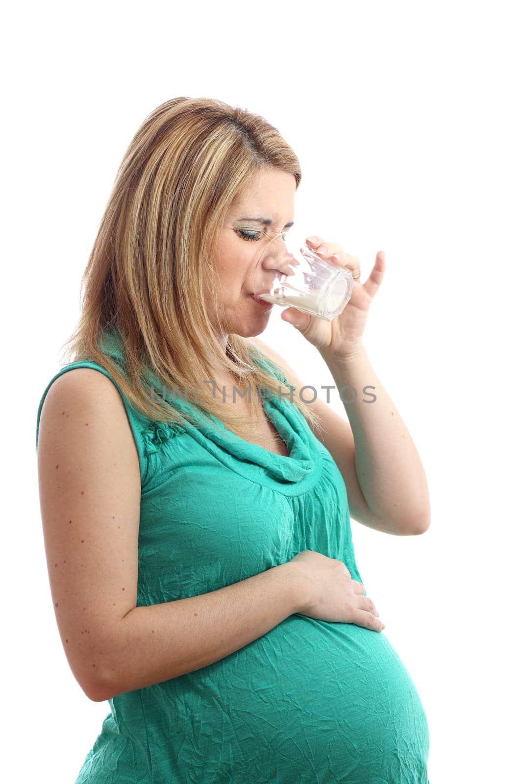A pregnant woman is drinking a glass of milk and she doesn't like it!