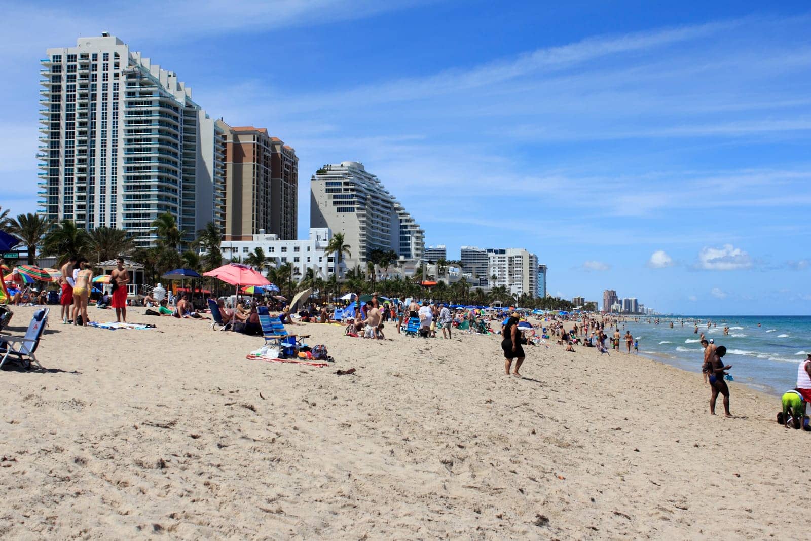 FORT LAUDERDALE, FLORIDA - APRIL 8, 2013: Long distance view of public beach filled with many people on spring break vacations, enjoying the warm sunny weather on the sand and in the Atlantic ocean.