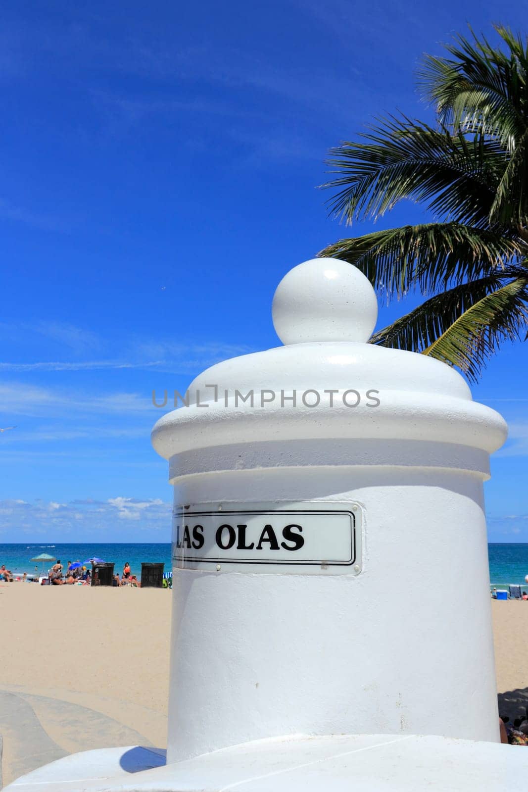 FORT LAUDERDALE, FLORIDA - APRIL 8, 2013: Entrance sign to Las Olas beach at the end of Las Olas Boulevard and A1A with a palm tree and people enjoying the sunny Atlantic Ocean coast during the day.