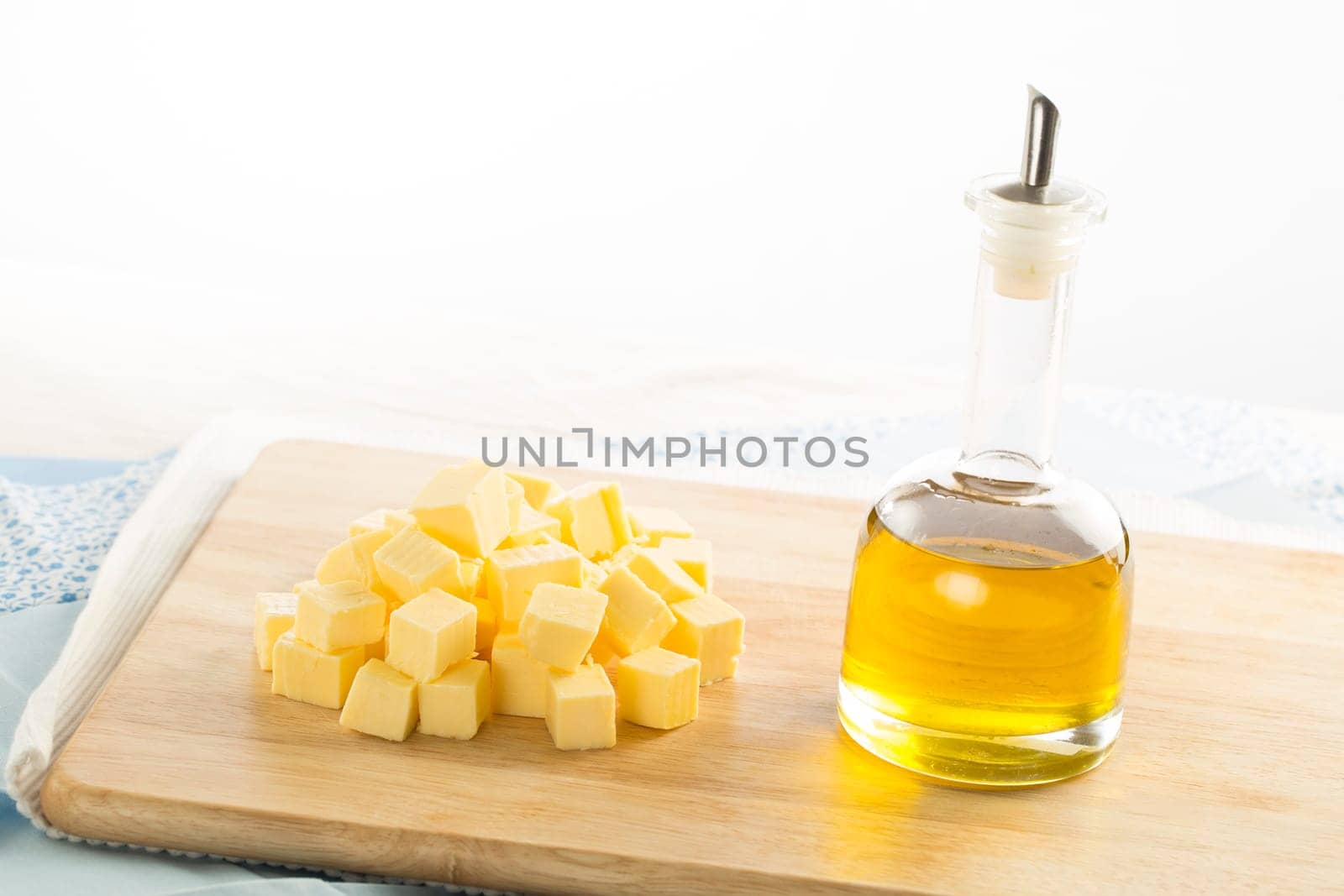 Olive oil in bottle and butter cubes on food preparation surface.
