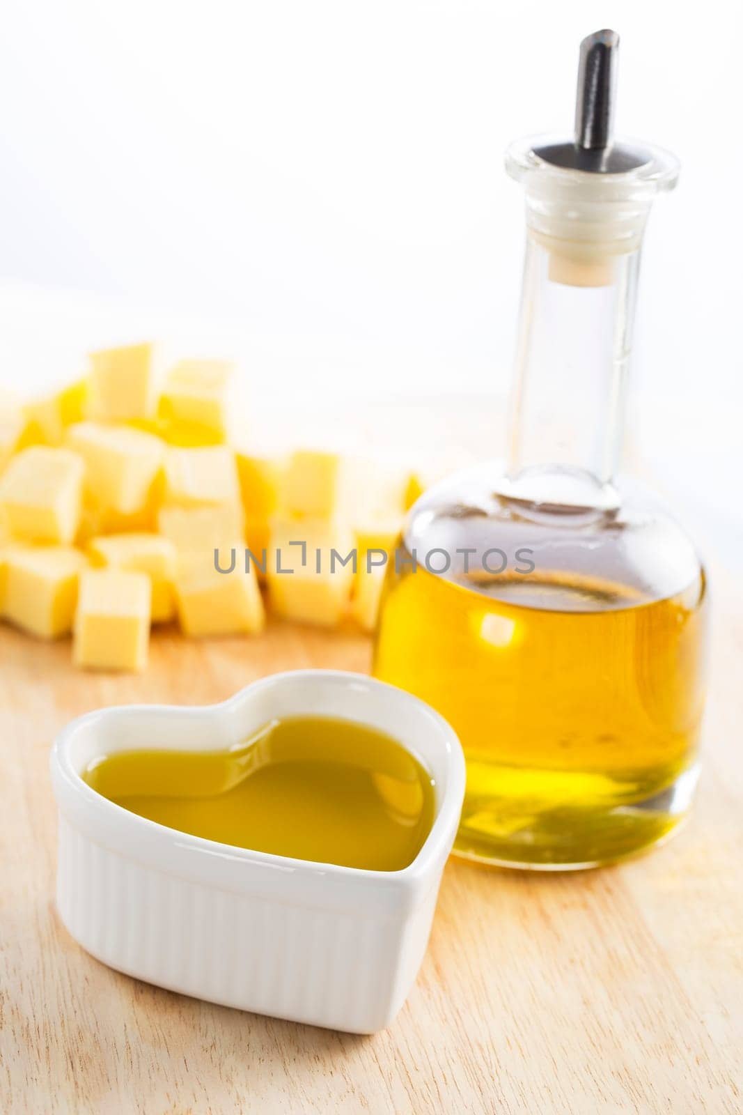 Olive oil in bottle and in a heart with butter in the background