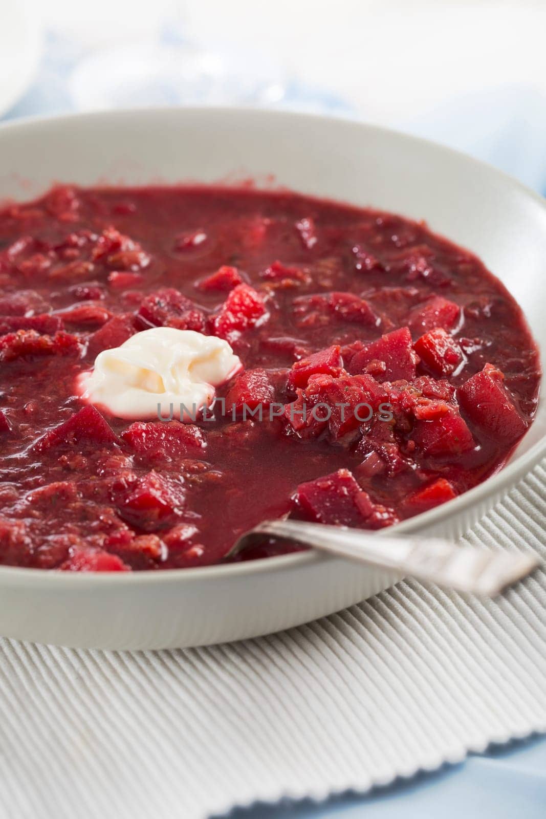 Bowl of homemade borscht soup with spoon and dollop of cream.