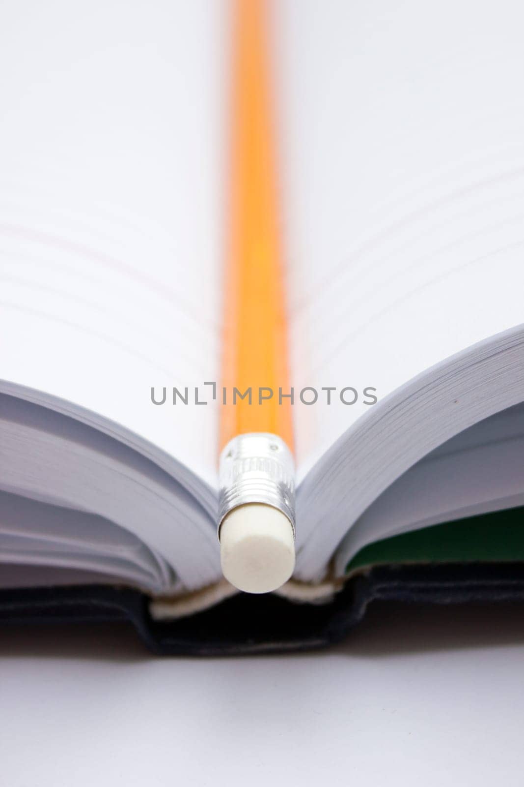 Pencil in a composition with a blank book with hardcovers.