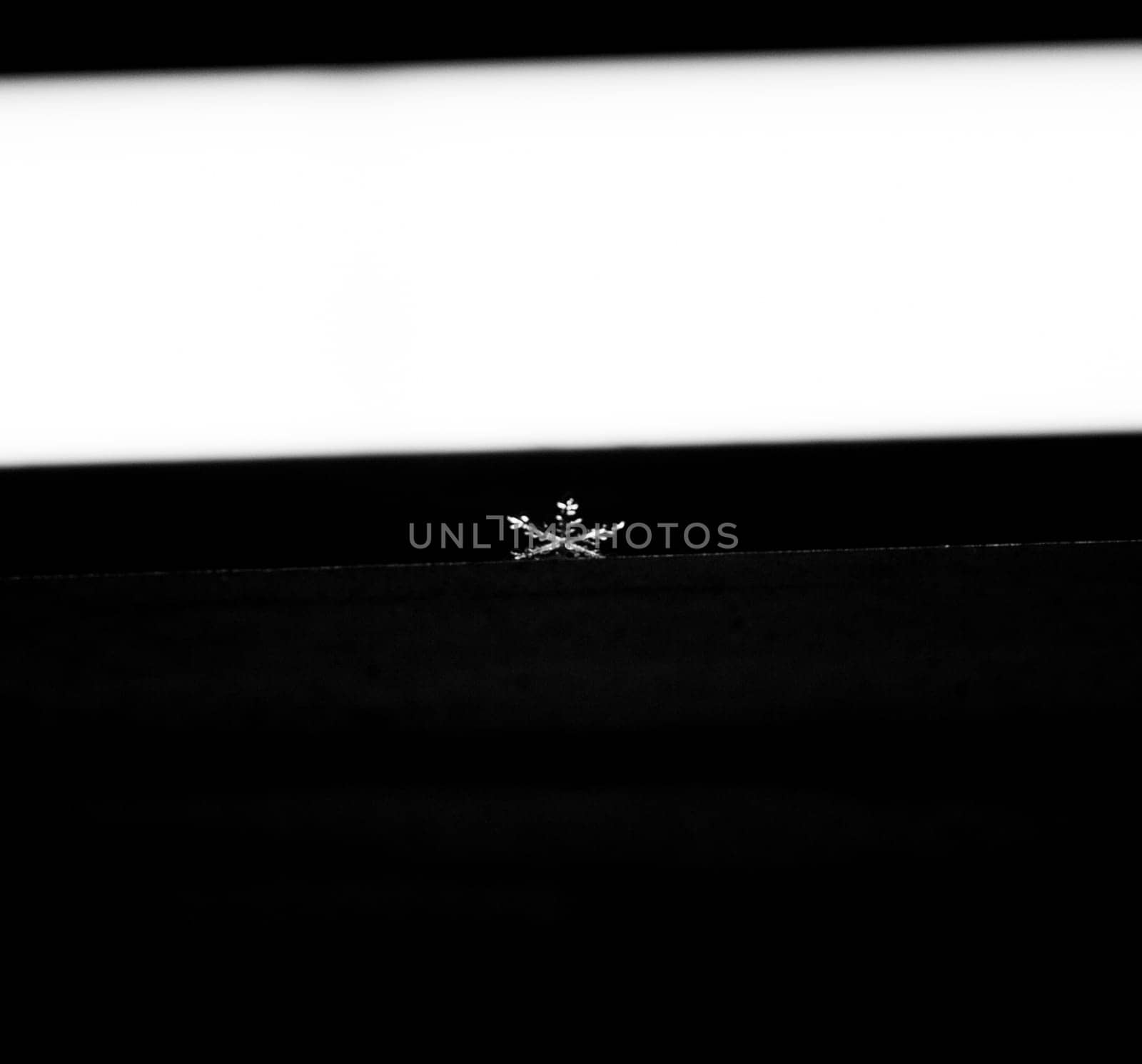 Snowflake falling on a window frame while it's snowing outside.