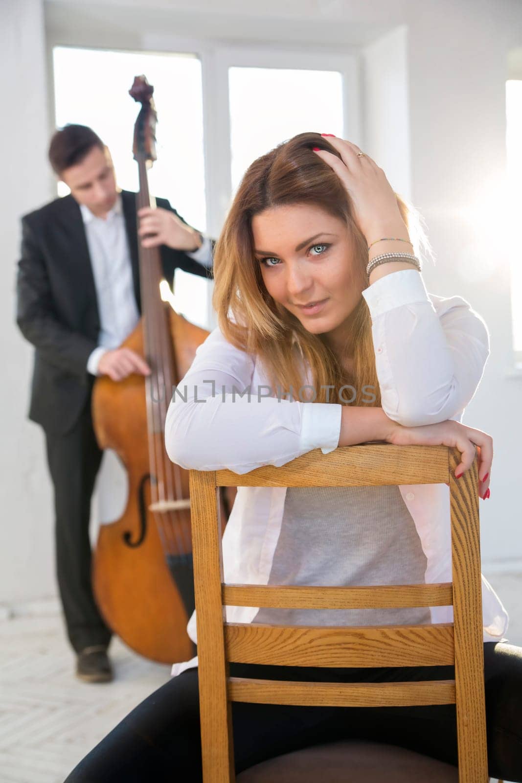 Young woman on chair and man with contrabass