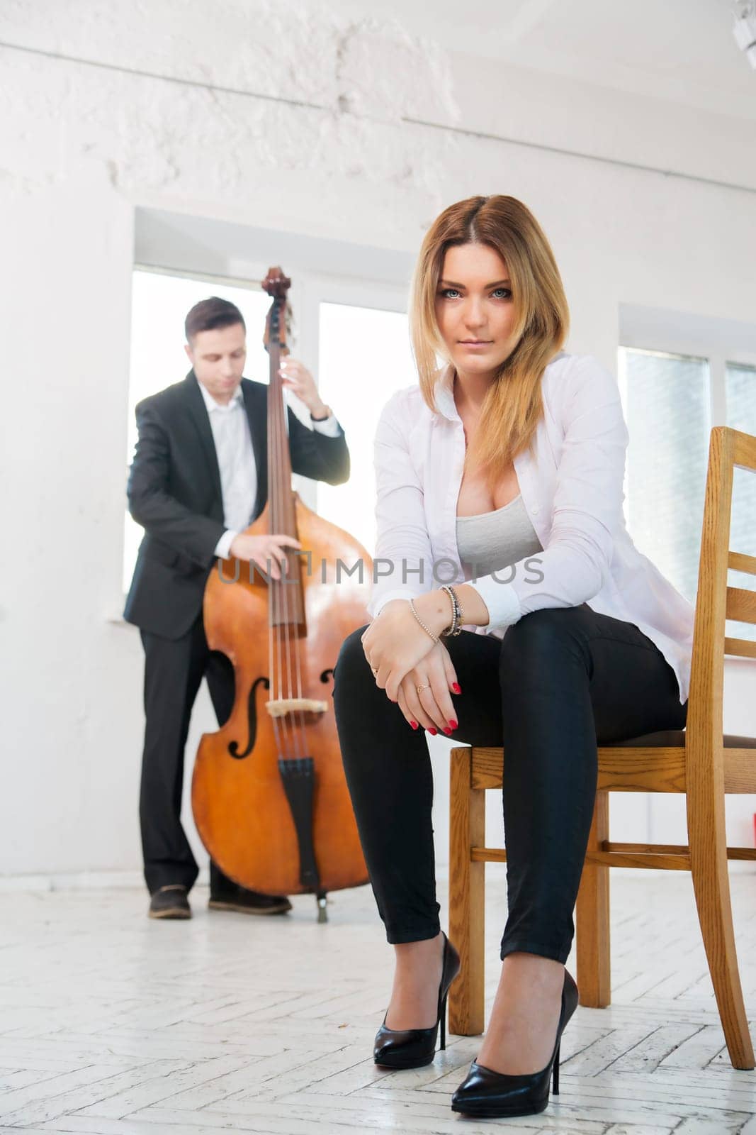 Young woman on stool and man plays melody