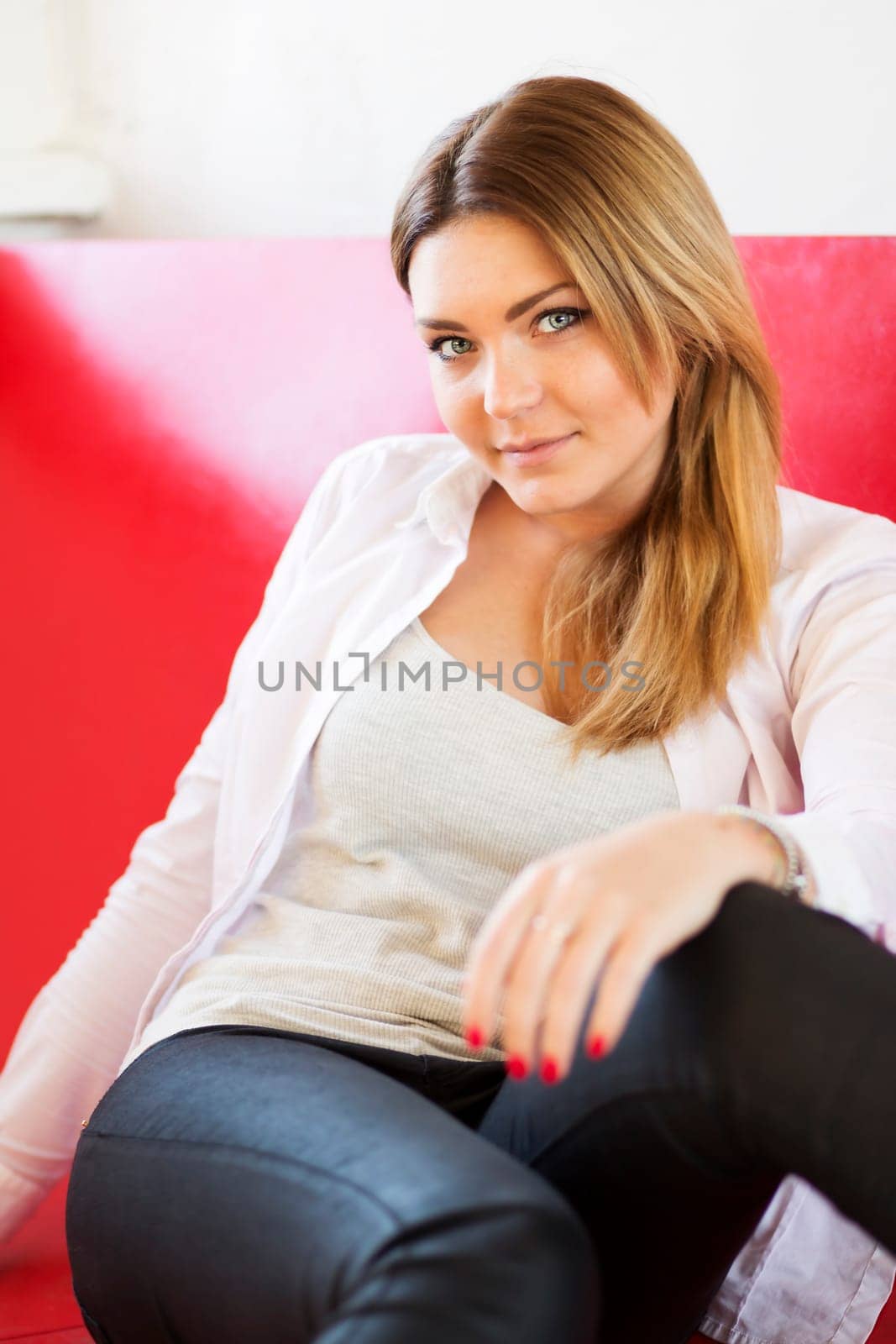 Woman on monotonous red sofa from imitation leather