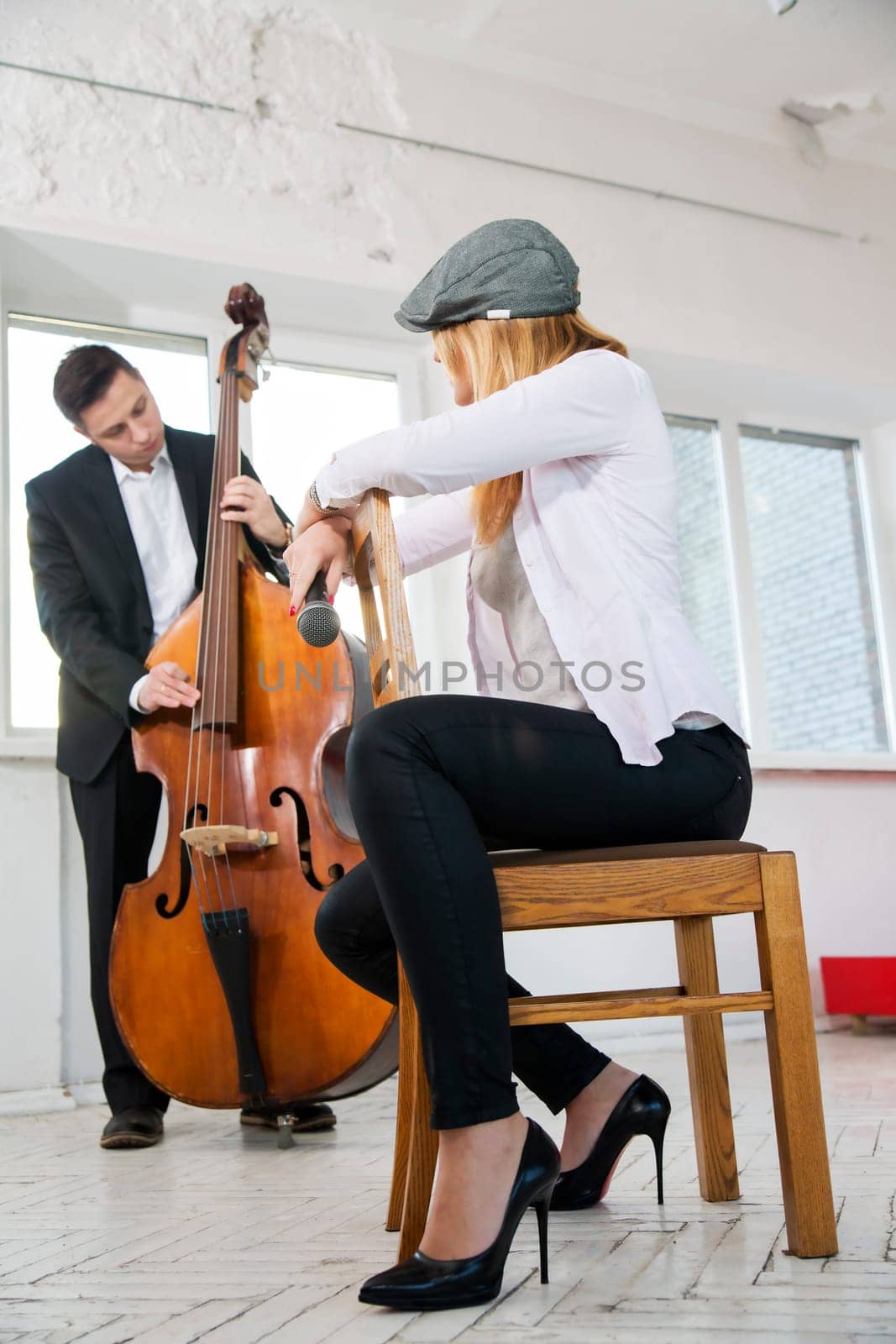 Woman backwards on chair listen man contrabass play
