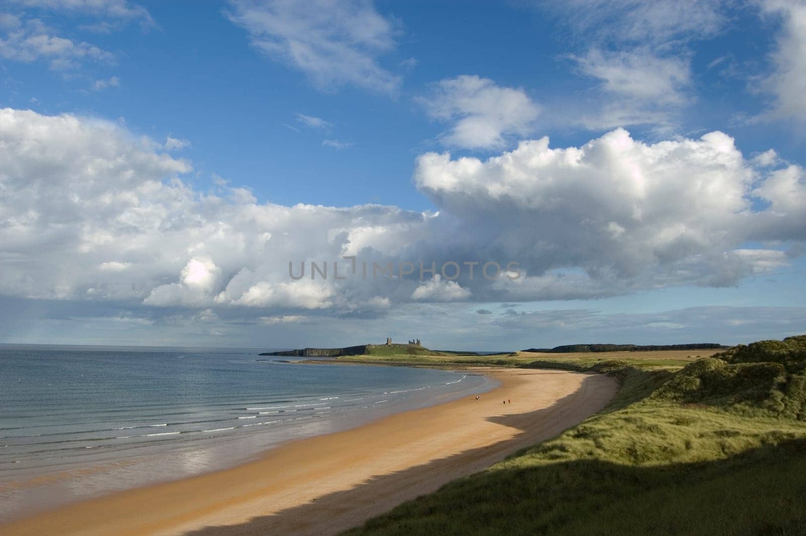 The ruin of Dunstanburgh Castle in the distance beyond the sands of Embleton Bay
