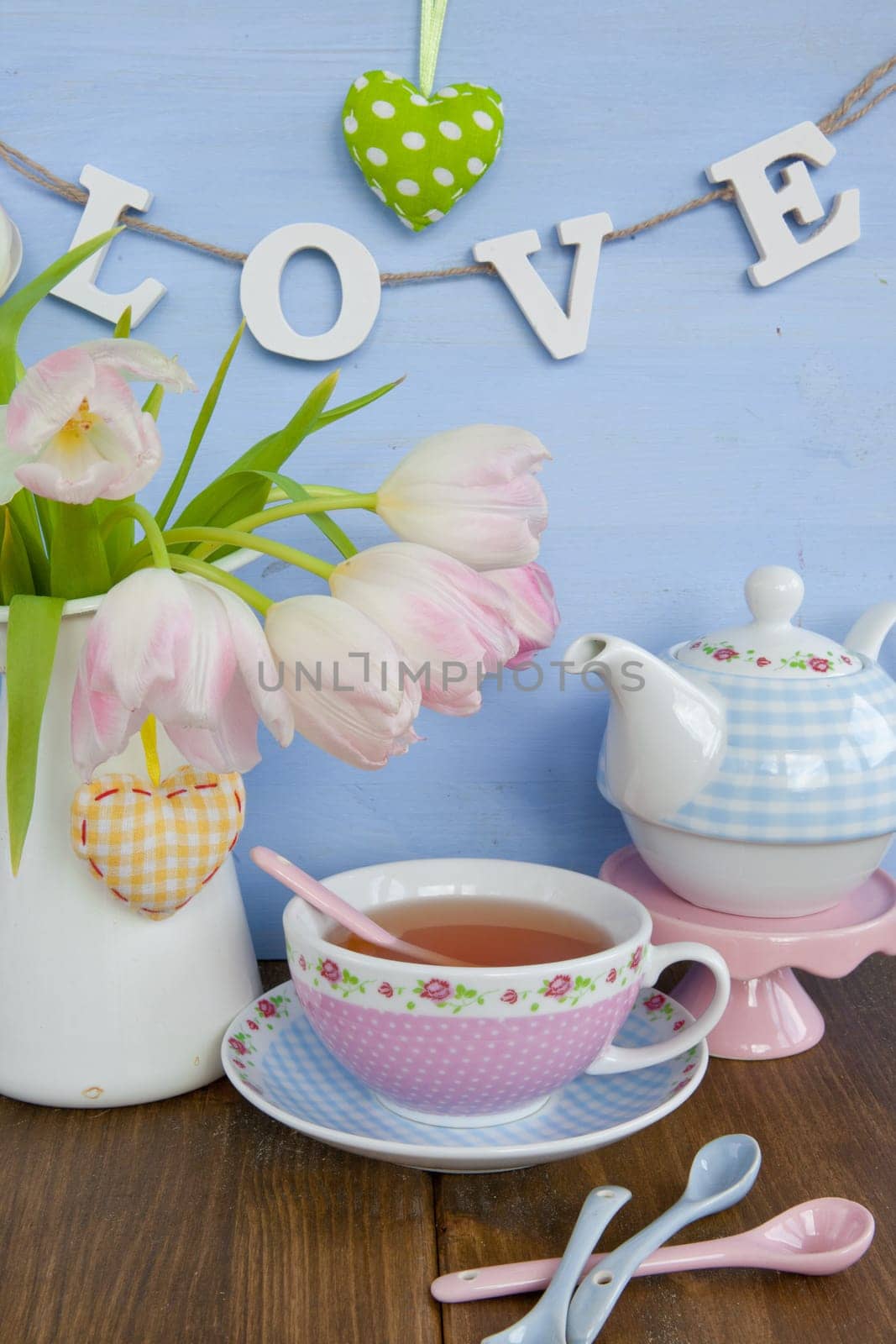Fresh tea in a colourful cup and tulips in a vase