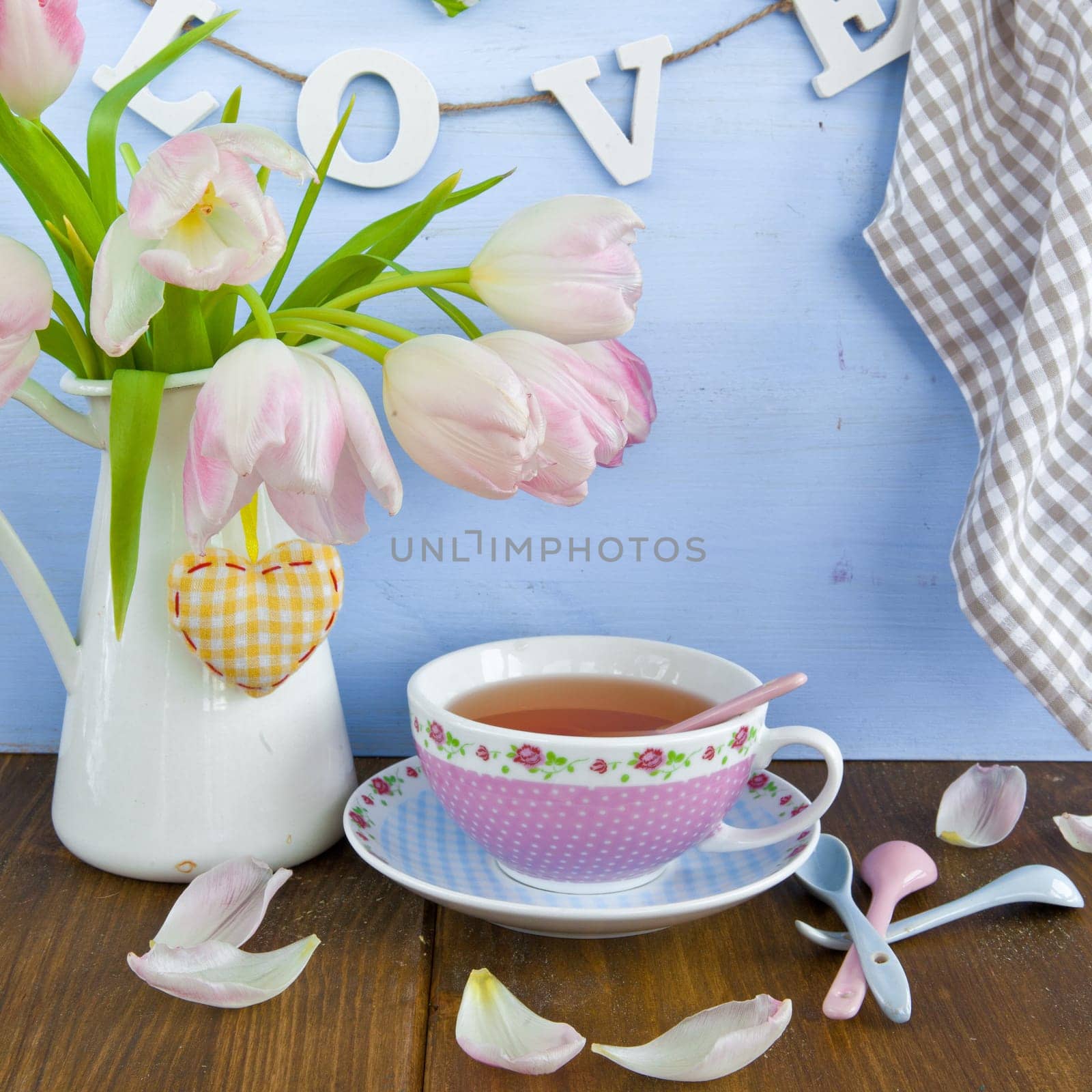 Fresh tea in a colourful cup and tulips in a vase