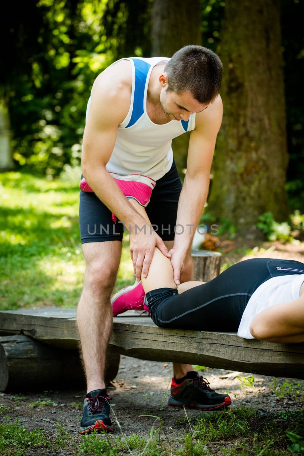 Man gives massage of calf to his friend after sport training outdoor