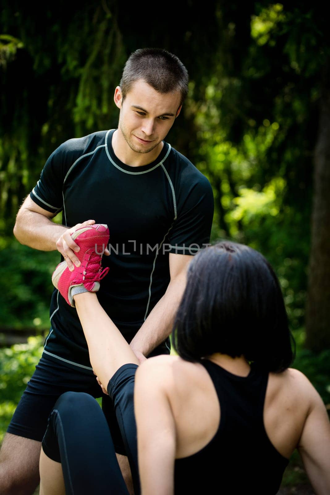 Man helps woman with muscle spasm - stretching her leg