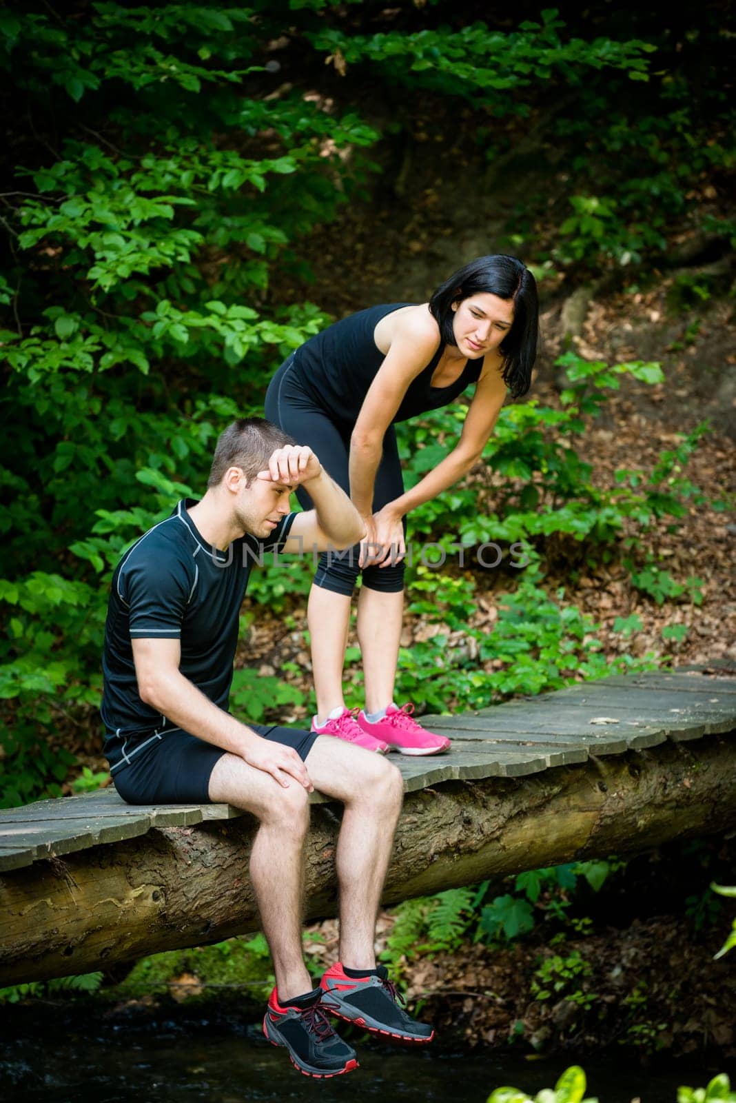 Sport couple relaxing after jogging in nature (foot bridge in forest)