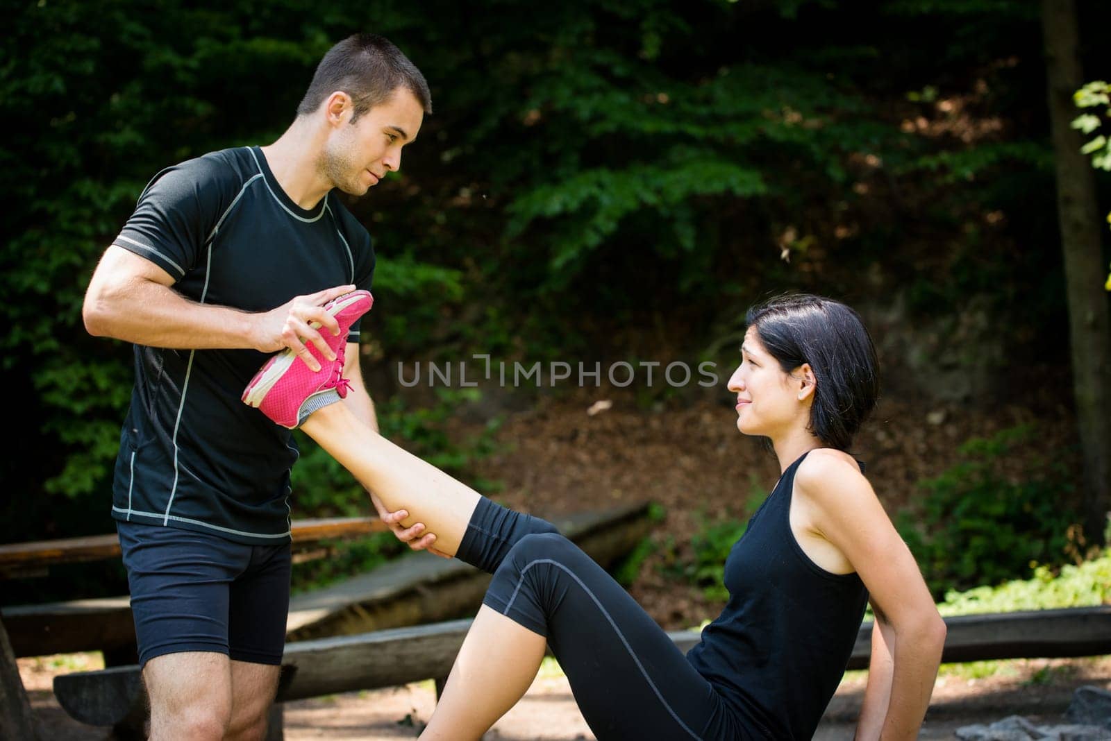 Man stretches womans leg - muscle spasm after sport training