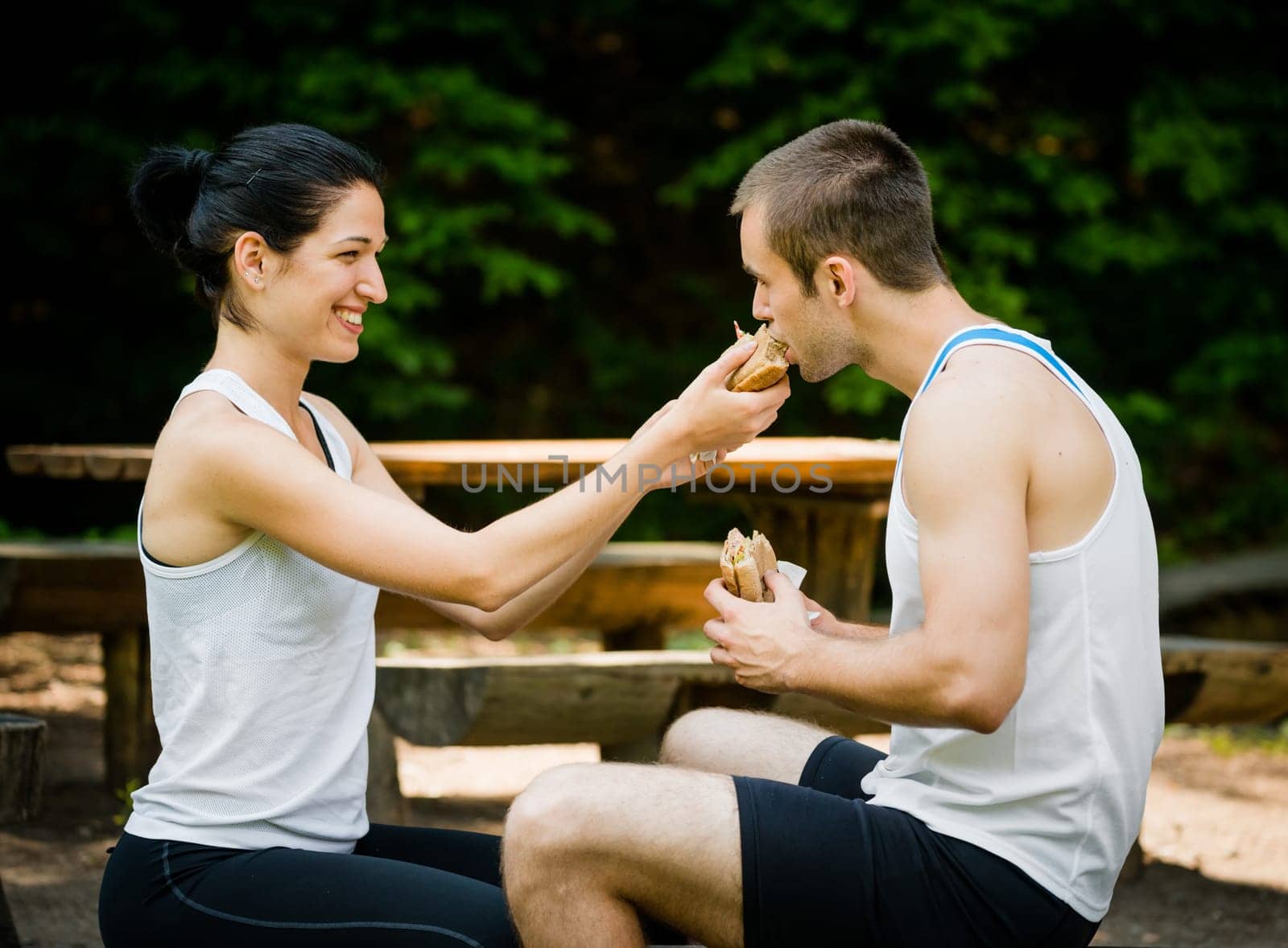 Young sport couple eating after jogging - woman feeding man