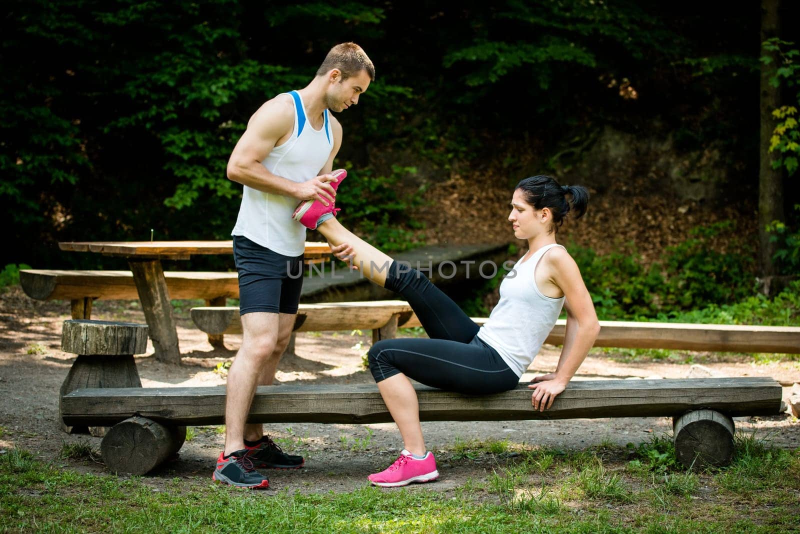 Man stretches womans leg - muscle spasm after sport training