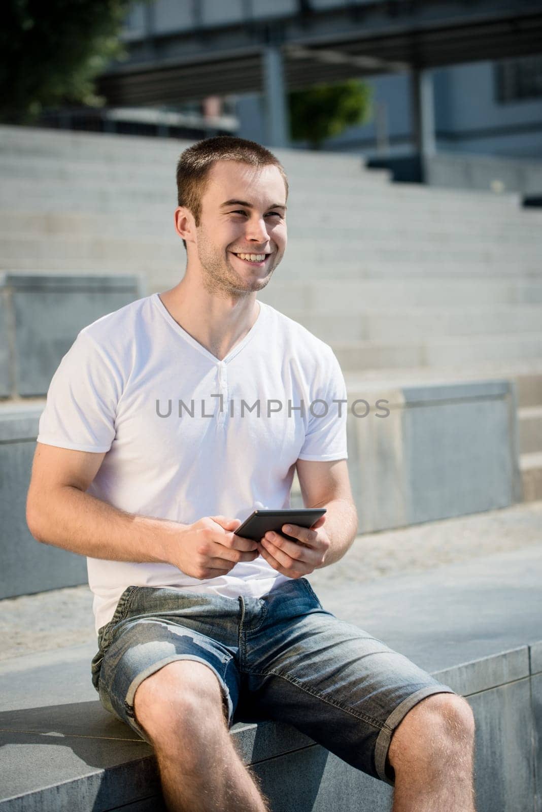 Young smiling man working with tablet - outdoor in town