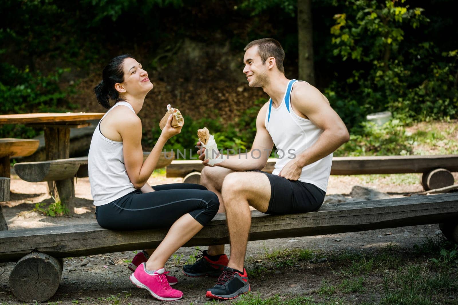 Young couple having fun while eating after sport training outdoor in nature