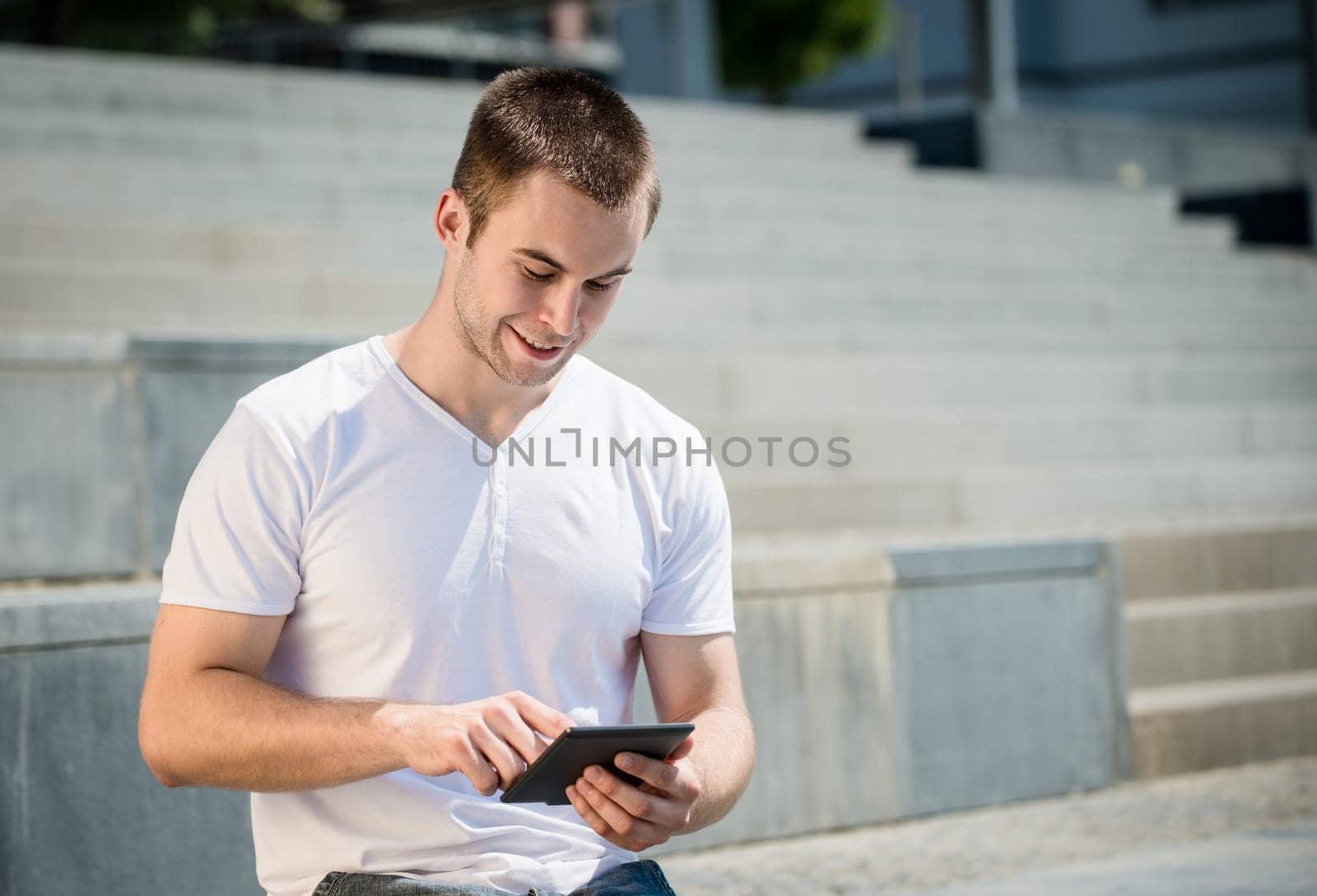 Young smiling man working with tablet - outdoor in town