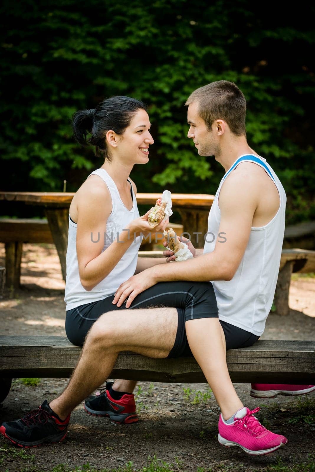 Young couple eating together after jogging outdoor in nature