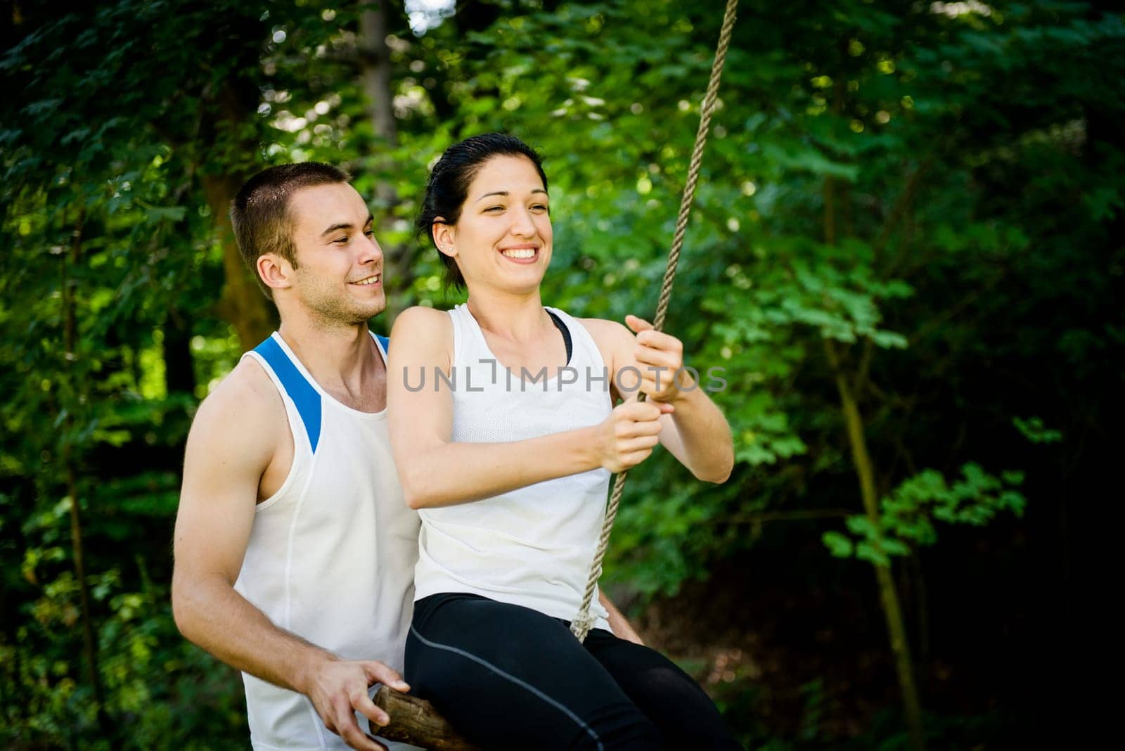swinging on seesaw - young sport couple having fun