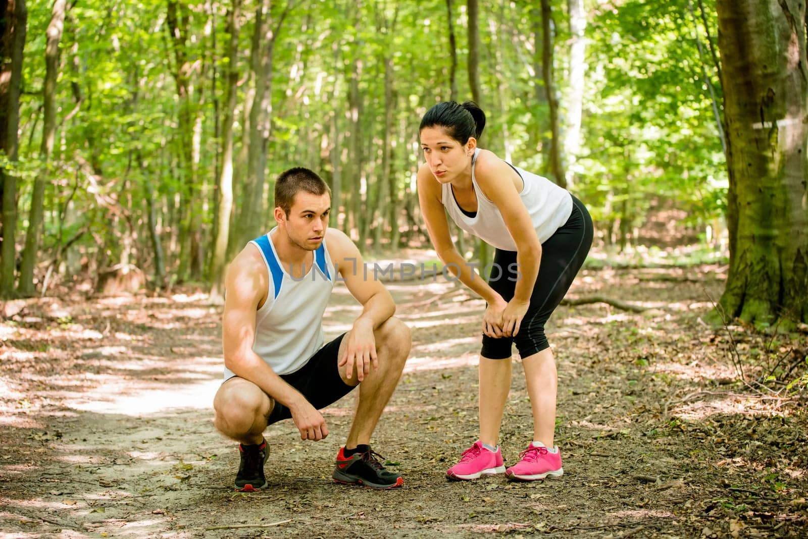 Young sport couple tired after jogging relaxing in nature (forest)