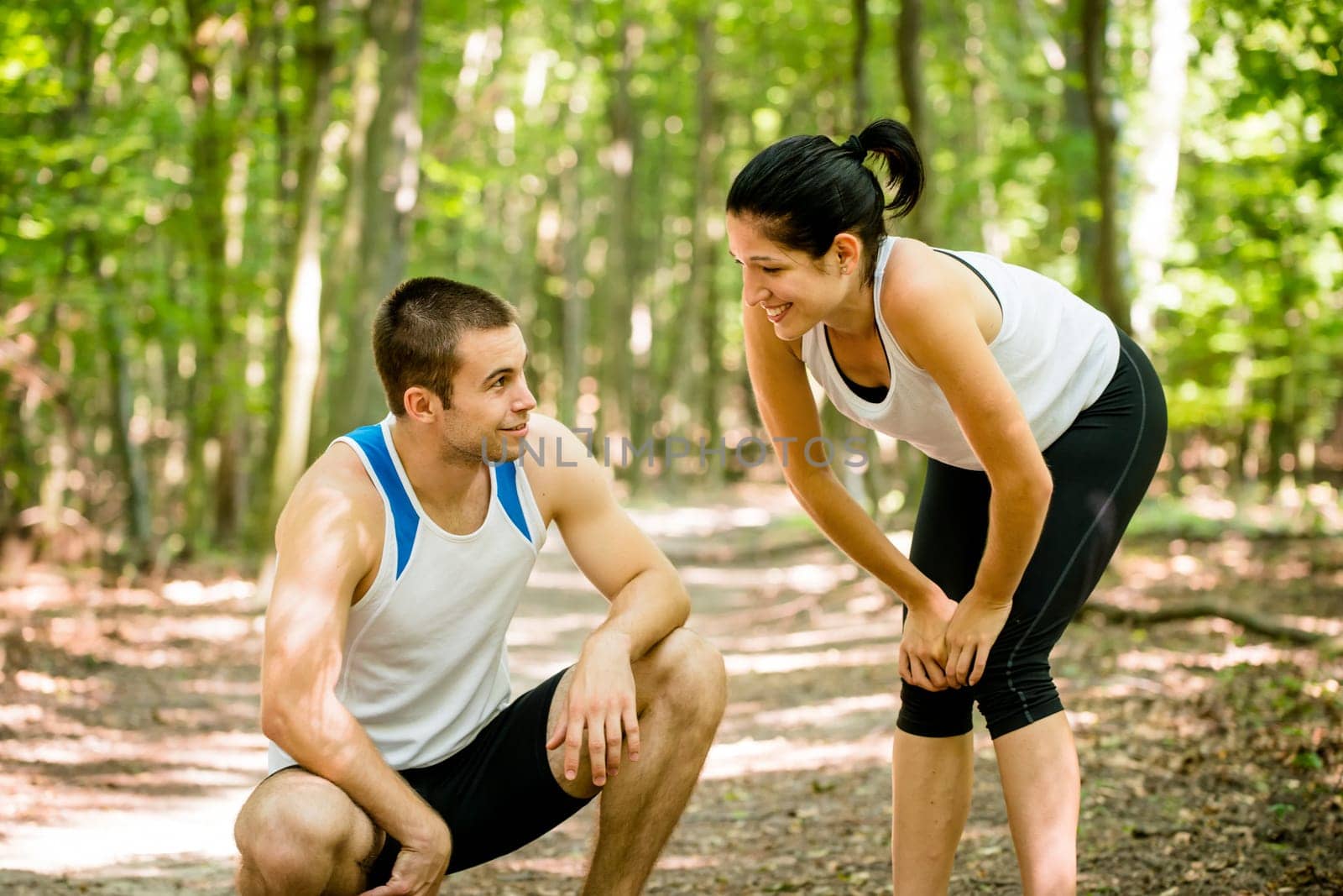 Young sport couple tired after jogging relaxing in nature (forest)