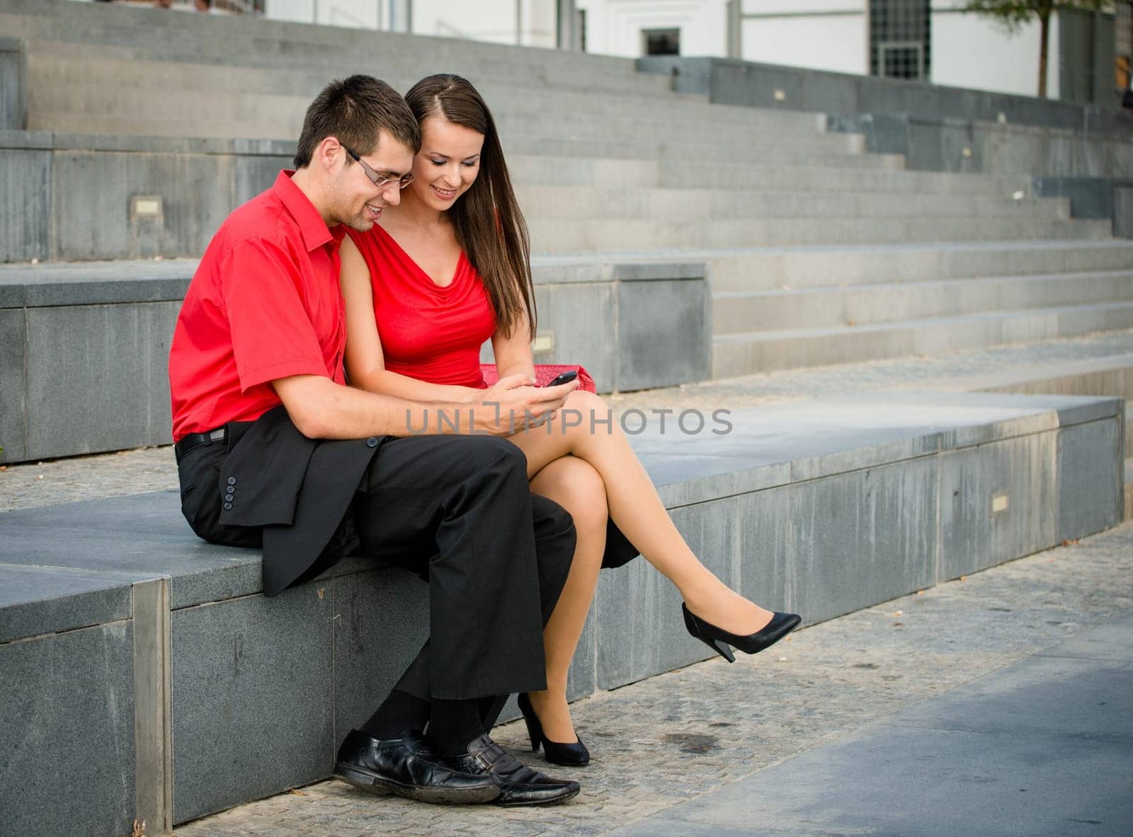 Colleagues - young business people having conversation and showing something on mobile phone