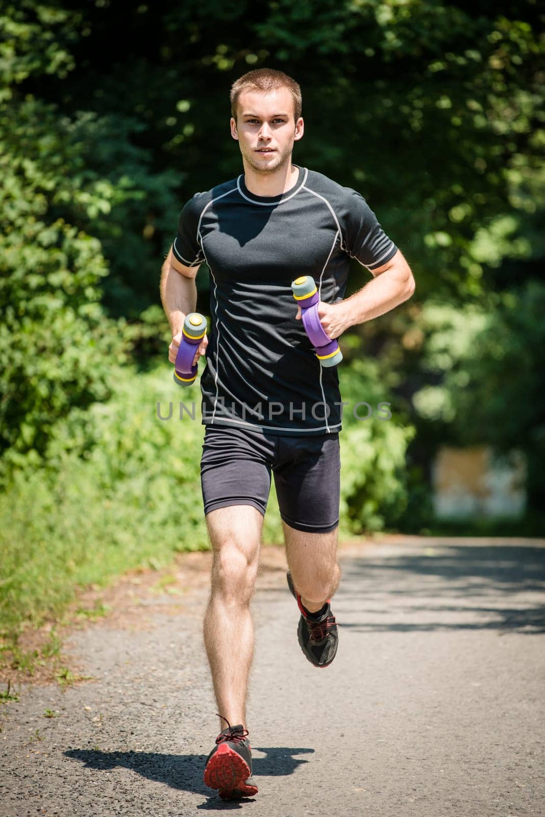 Jogging in nature - young man training with barbells