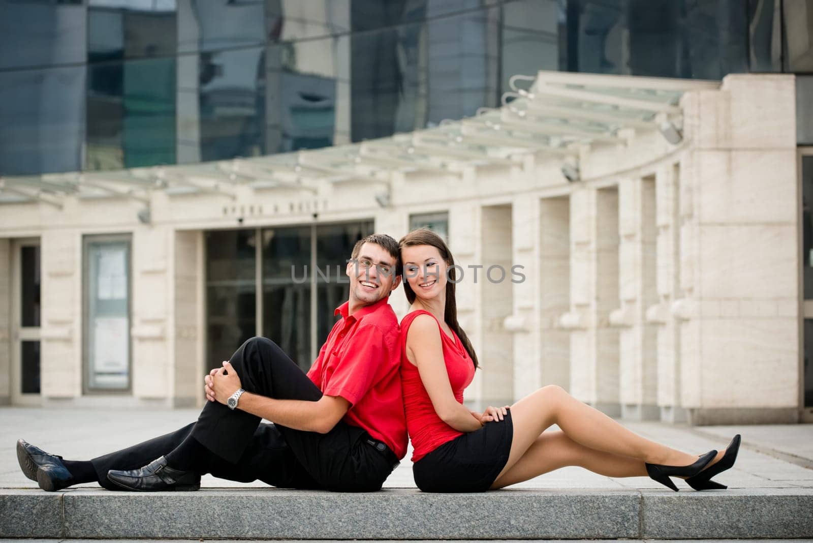 Young business couple relaxing leant with backs on street