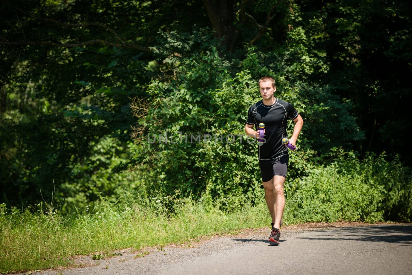 Jogging in nature - young man training with barbells