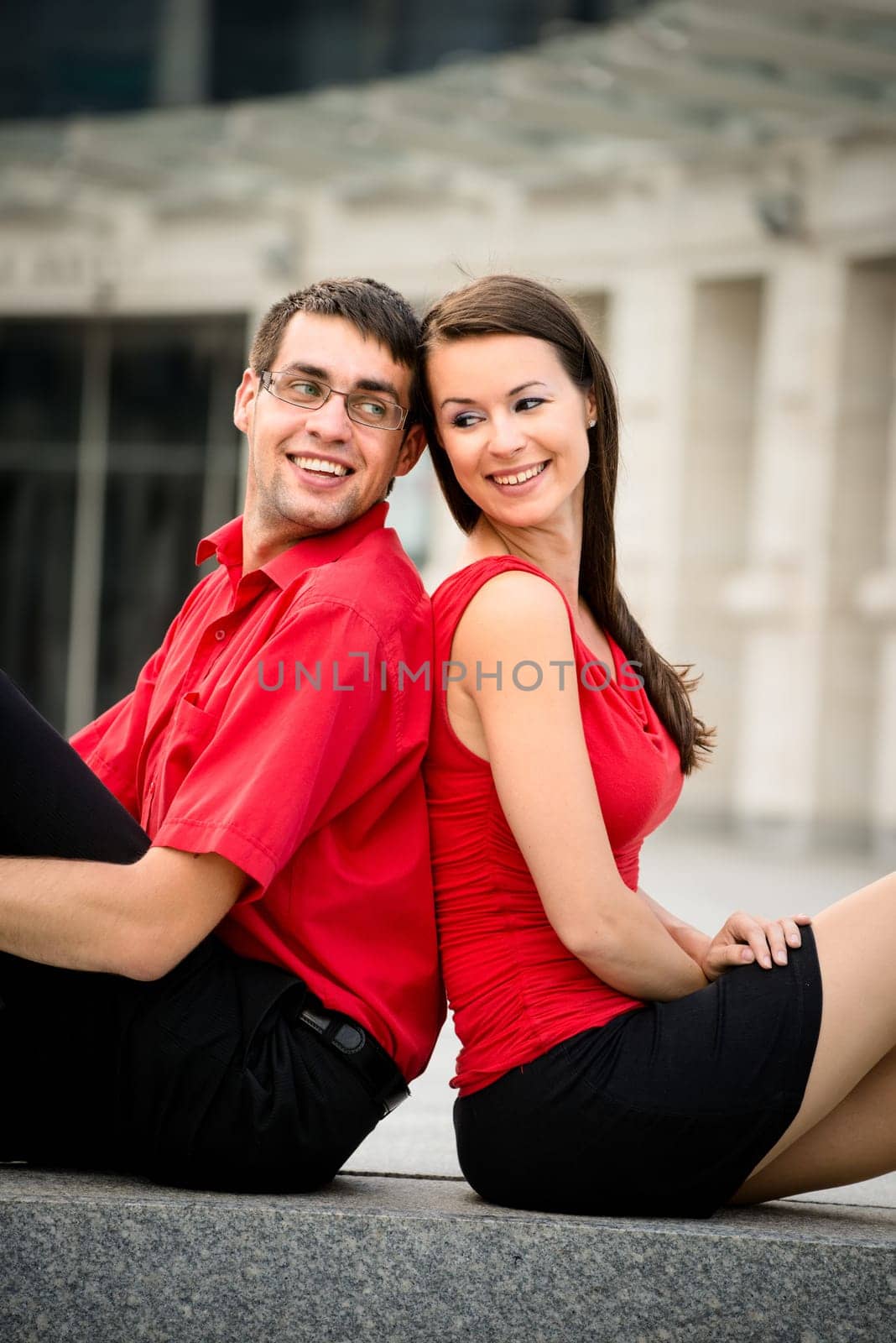 Young business couple relaxing leant with backs on street