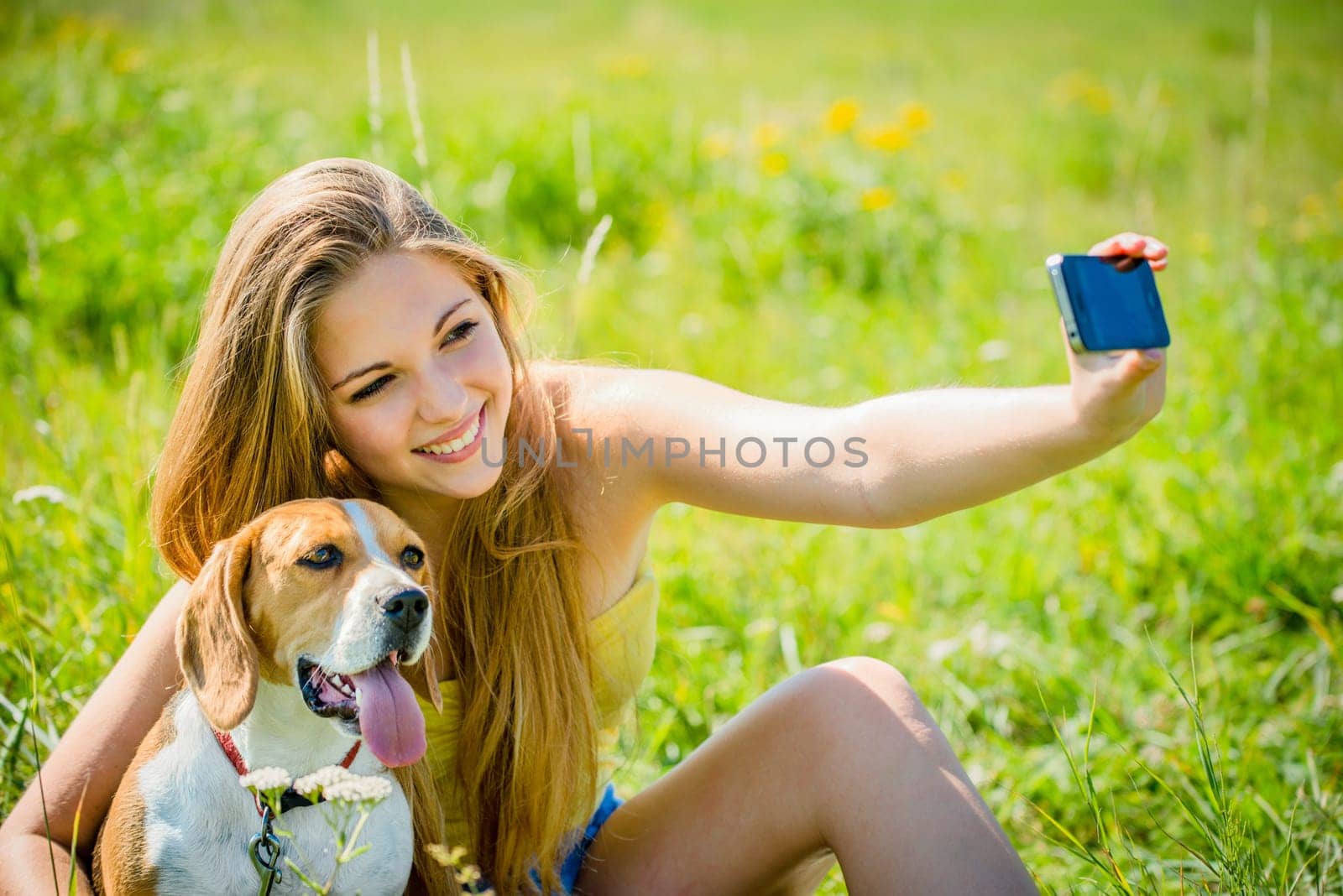 Teen girl taking photo of herself and her dog with mobile phone camera