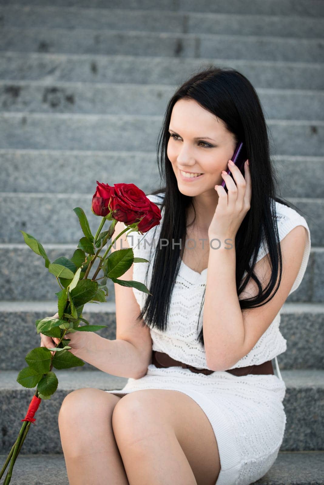 Young beautiful woman with red roses calling with mobile phone