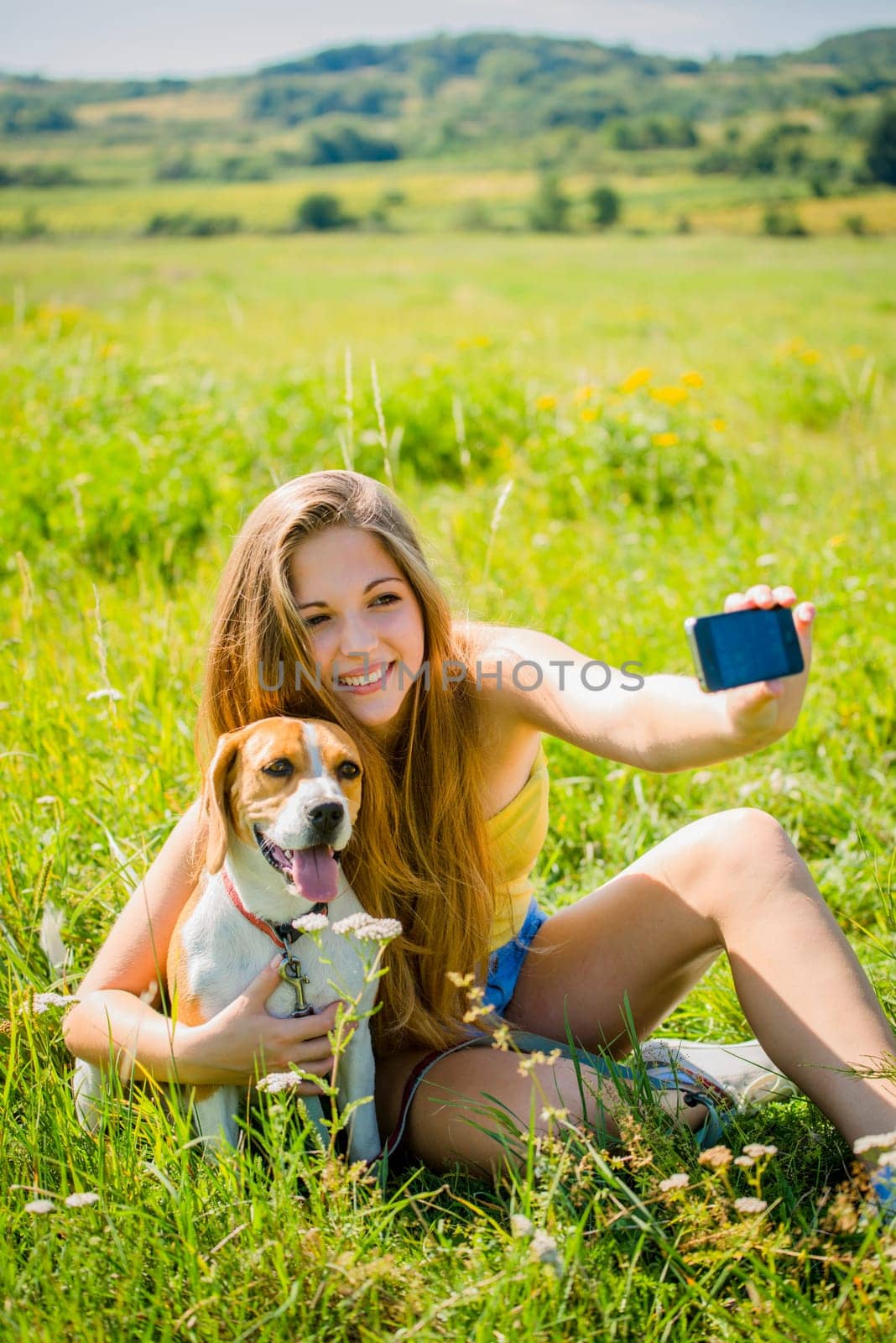 Young woman taking photo of herself and her pet with mobile phone camera