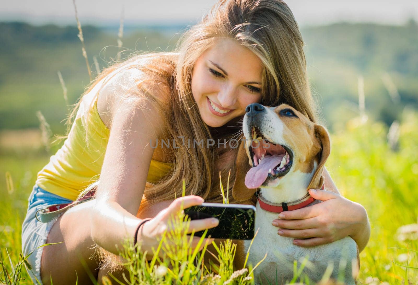 Teen girl taking photo of herself and her dog with mobile phone camera