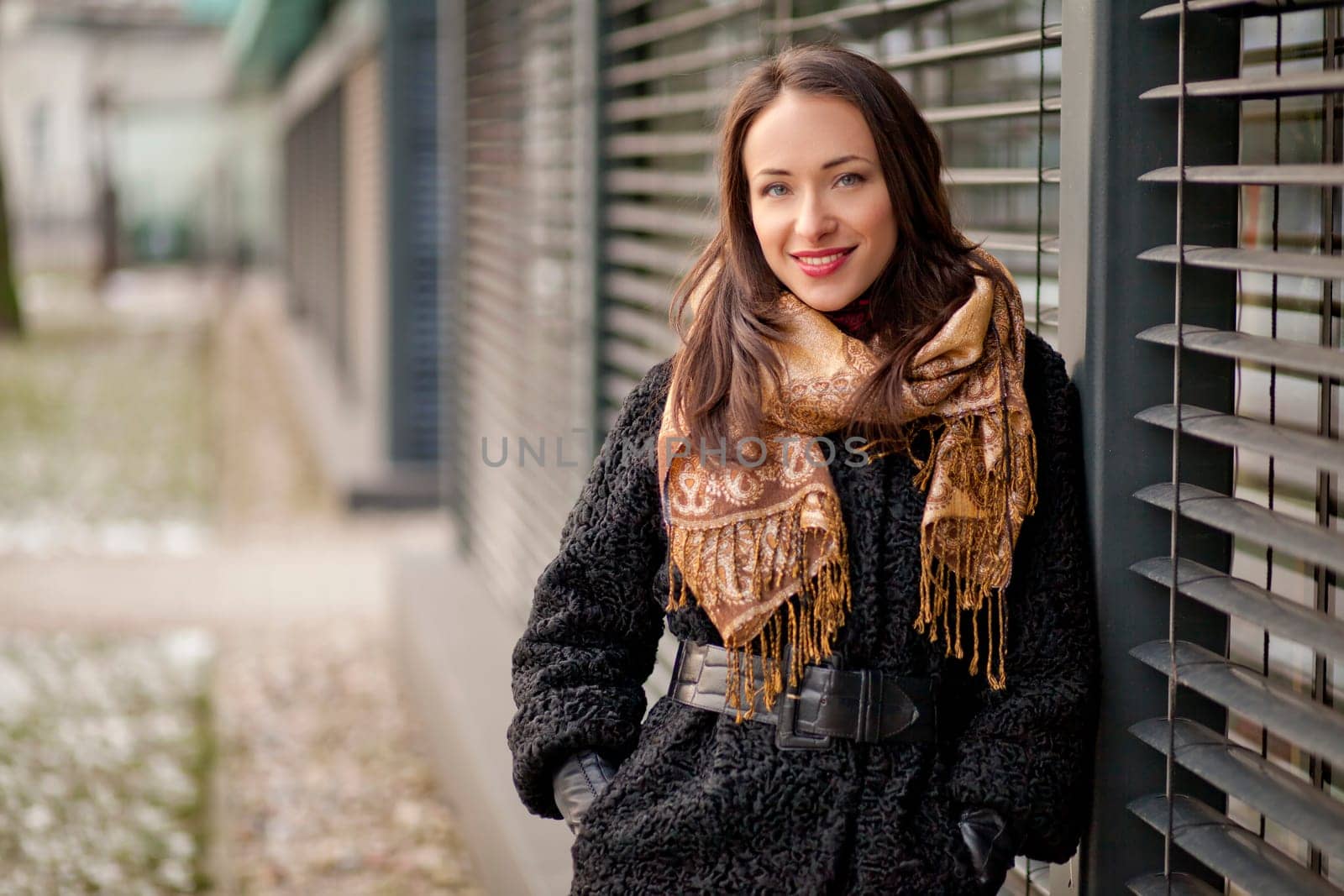 Young pretty lady is standing by the louvers and enjoying winter