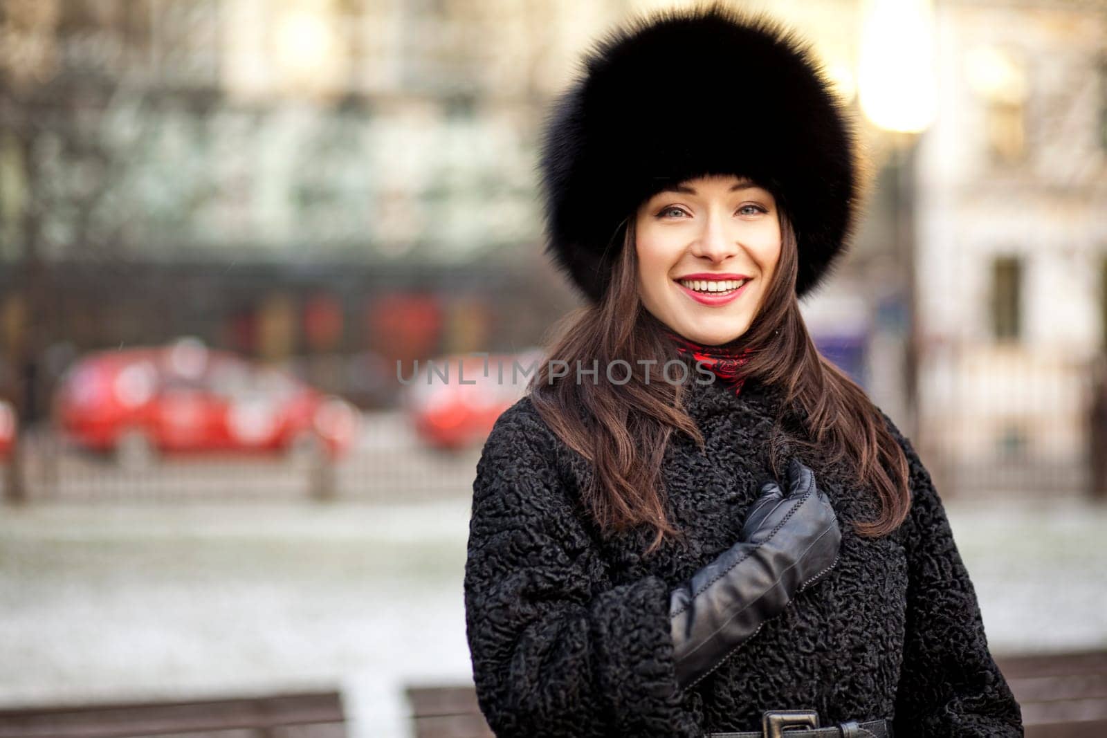 Winter girl wearing fur hat, coat and gloves in park