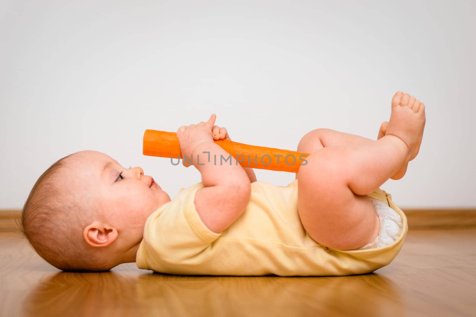 Baby exploring carrot indoors - healthy living