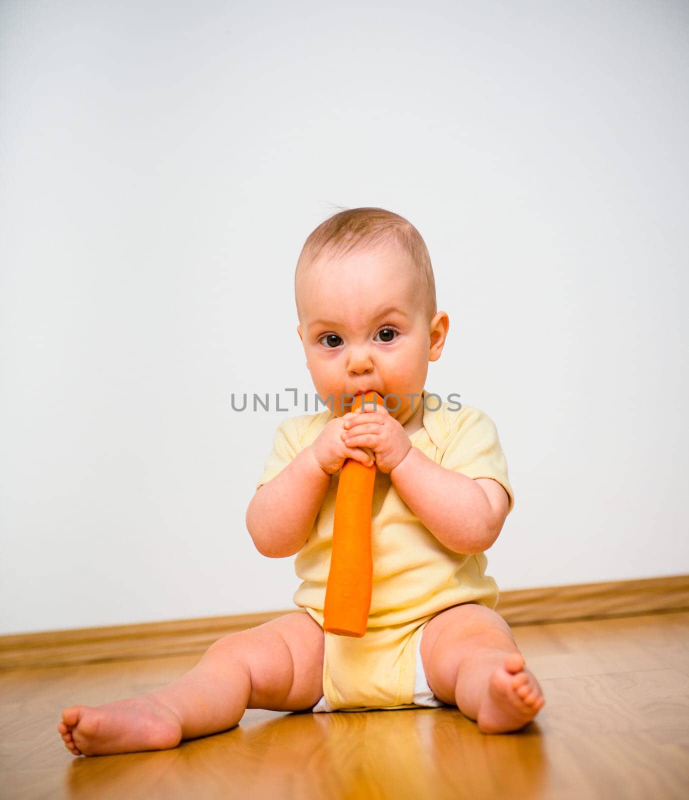 Baby eating carrot indoors - healthy living