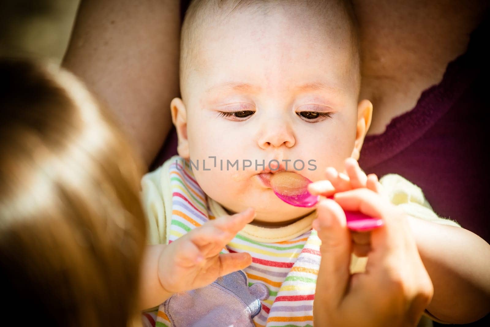 Mother feeds her baby with spoon, close-up on face