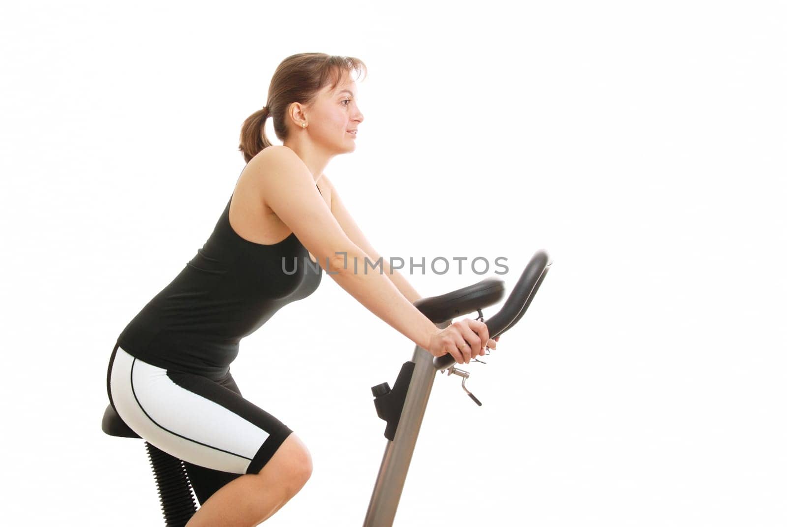 Isolated young womanexercising on a spinning bicycle - profile