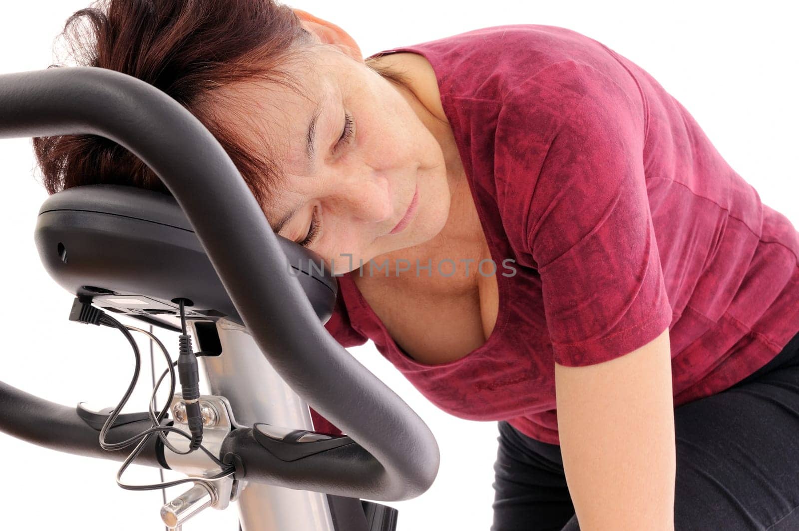 Tired senior woman on spinning bicycle - isolated