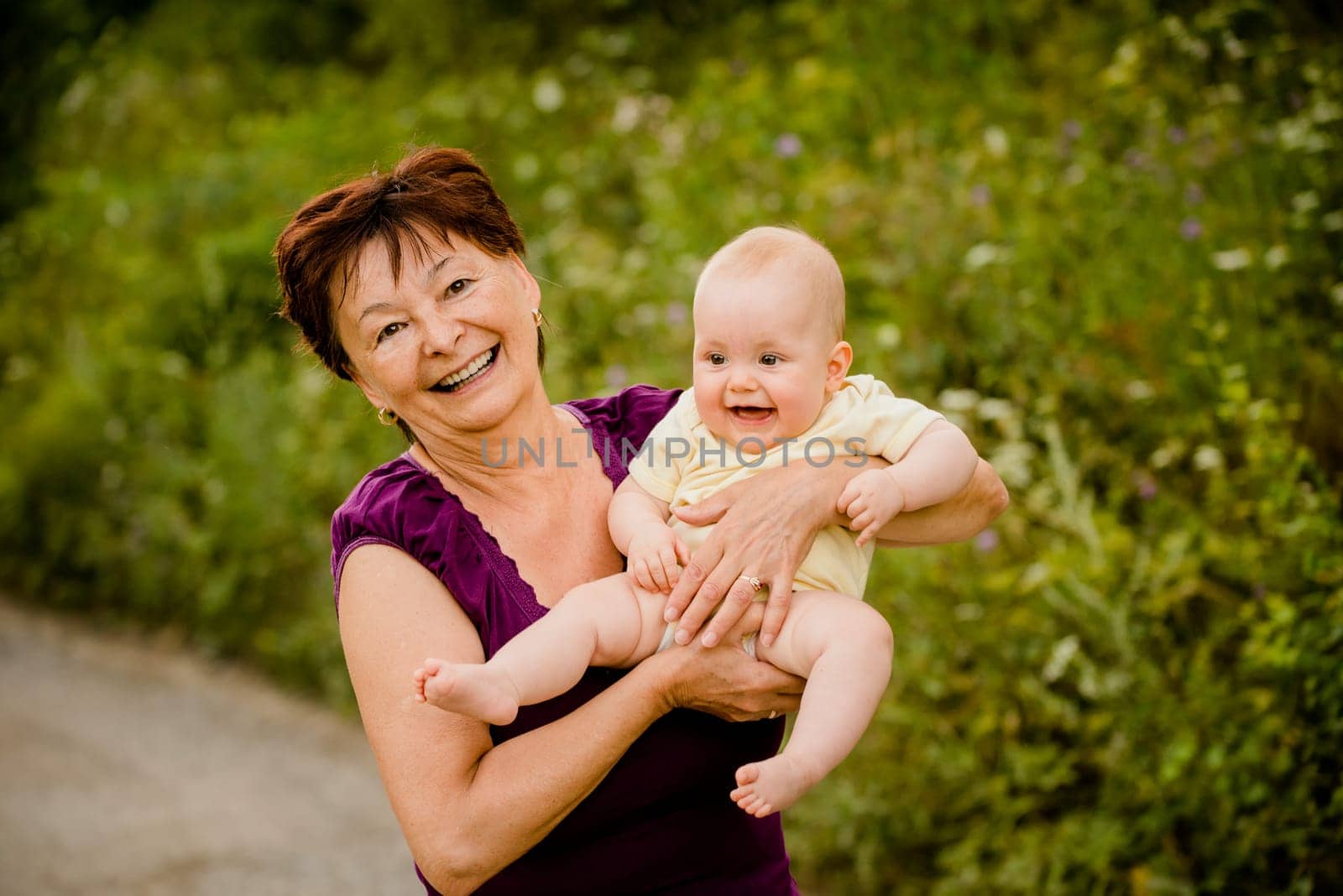 Grandmother with grandchild - senior woman holding her granddaughter outdoor in nature