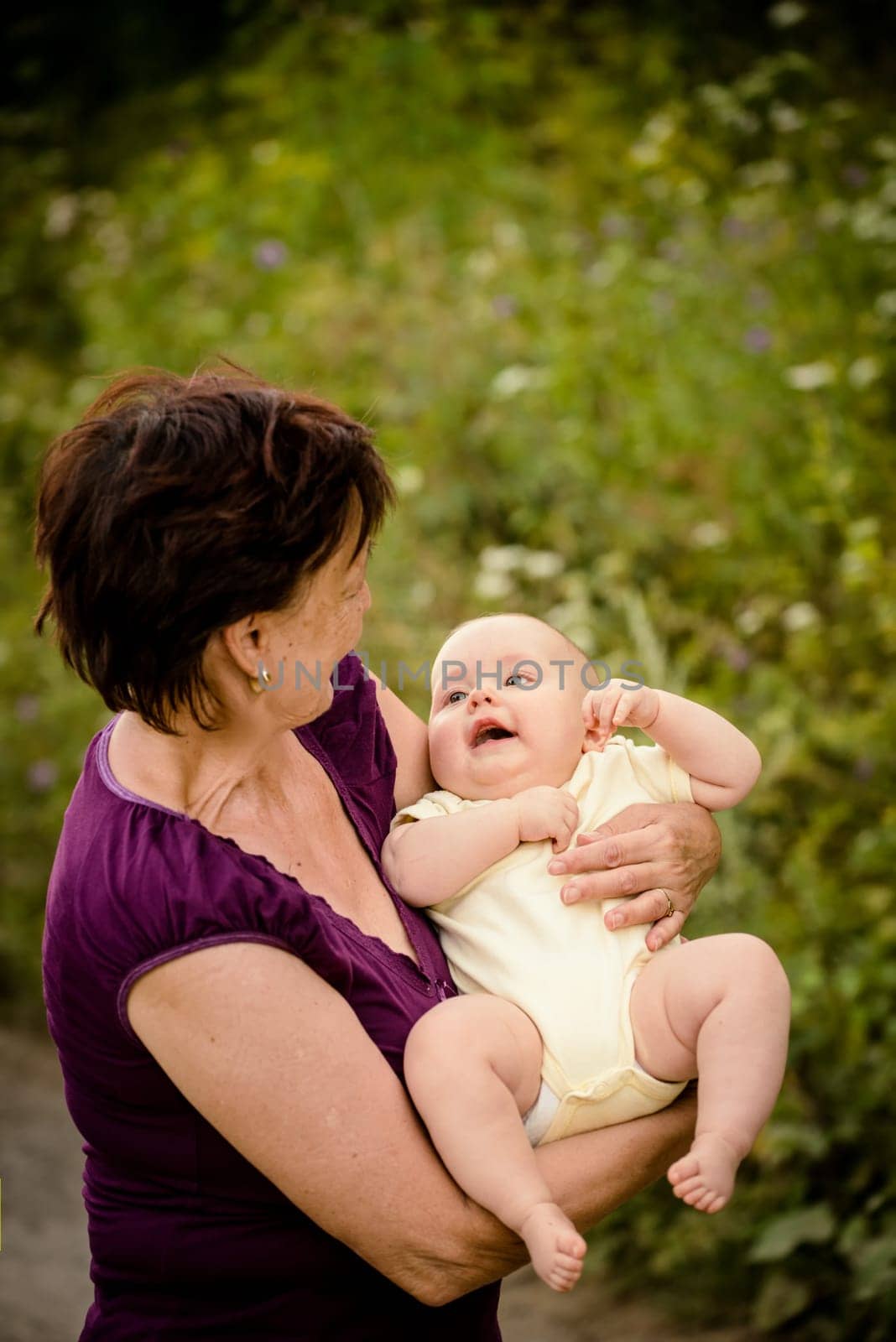 Grandmother with grandchild - senior woman holding her granddaughter outdoor in nature