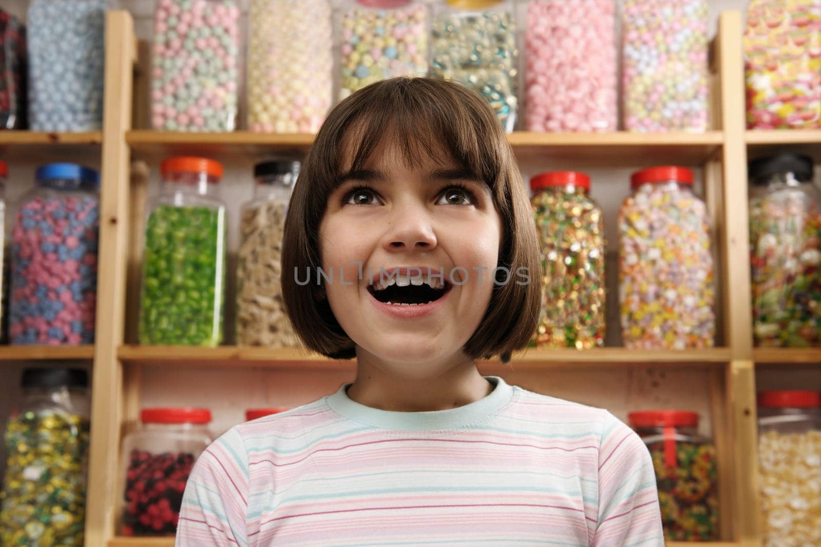 young girl smiling in awe at rows of sweets