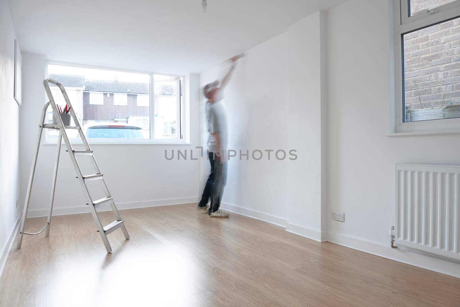 man decorating a room with ladder and paint pot in foreground